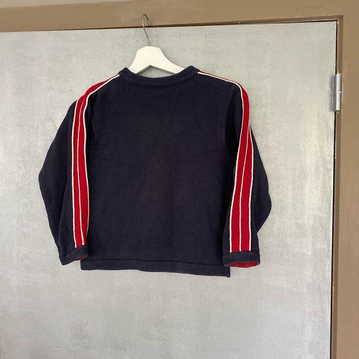 Pull en mailles bleu marine avec bandes rouges sur les manches taille 4 ans